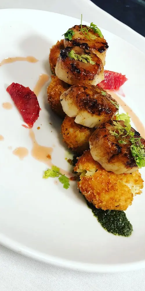 Seared sea scallops over crispy risotto cakes, with basil pistou and blood orange sauce. #fridaynigh