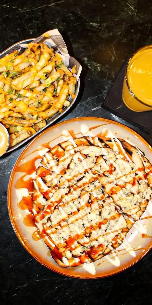 Pub food, redefined! 🔥 Our Buffalo Flatbread on naan, with grilled chicken, blue cheese crumble, and
